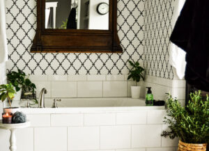 white tile tub surround with plants and bath accessories.