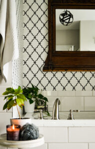 trellis wall paper in white and black. Bathroom with candle and small side table.