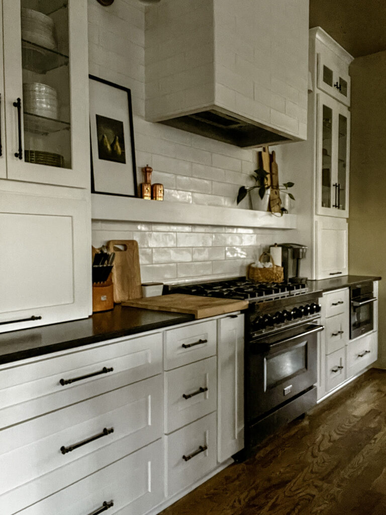 base cabinet view with black leathered granite tops, butcher block cutting block and a basket with coffee pods.