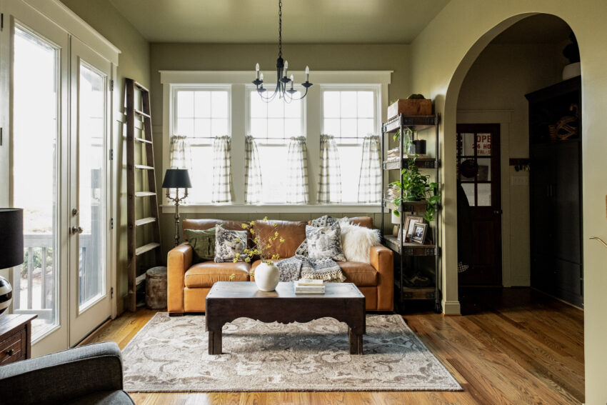 Full view of the old breakfast nook. Camel leather sofa, fur pillow, black and cream throw blanket, vintage ladder and the full view with the mudroom visible